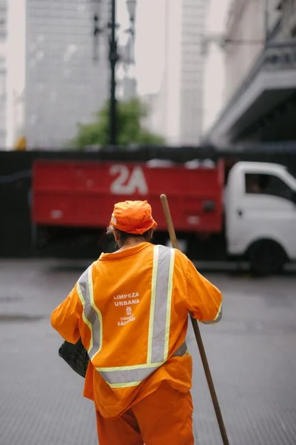 services-01 Une femme de ménage professionnelle en tenue rouge, tenant un aspirateur près d’un van, prête à intervenir.
